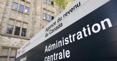 Une affiche de l'Agence du revenu du Canada devant un édifice de pierre.