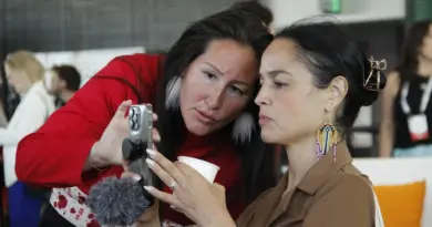 Qupanuk Olsen montre quelque chose sur son téléphone à une femme.