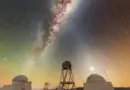 The Milky Way glows in a dark purple and orange night sky over the white domed buildings below. 