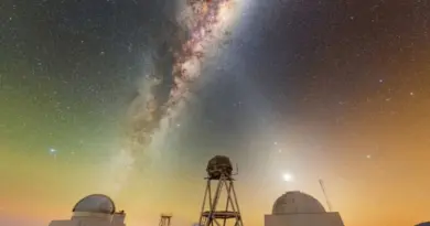 The Milky Way glows in a dark purple and orange night sky over the white domed buildings below.