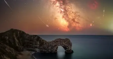 Perseid meteors are pictured alongside the Milky Way above a coastal scene featuring an arch-like rocky outcrop