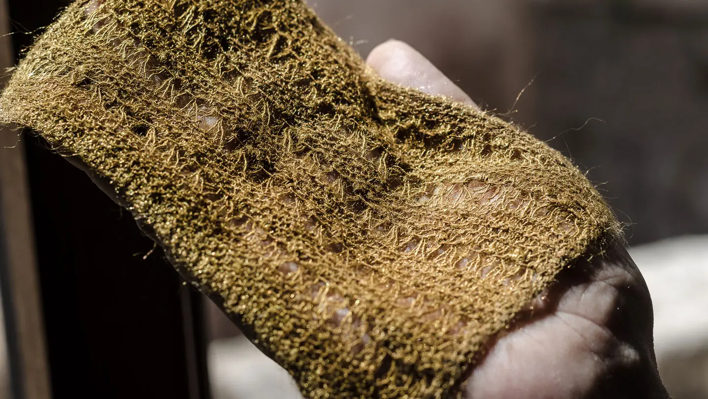 A hand holds a woven patch of sea silk