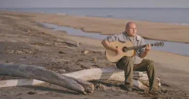 Un homme sur le bord de la plage avec sa guitare.