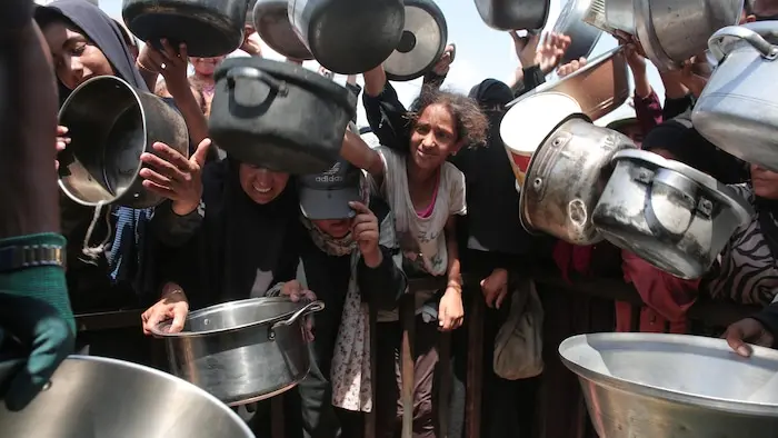 Des femmes et des enfants brandissent des casseroles vides.