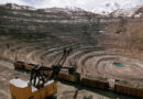 An excavator works inside of a large mining pit.