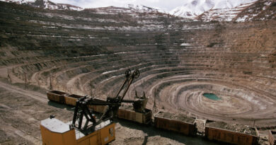 An excavator works inside of a large mining pit.