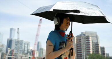 Une femme tient un parapluie pour se protéger du soleil, à Pékin, en Chine, le 23 juin 2025