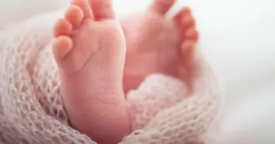 Zoom sur les pieds d’un bébé emmitouflé dans une couverture.