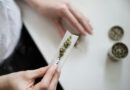 A person holding marijuana on a white paper.