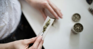 A person holding marijuana on a white paper.