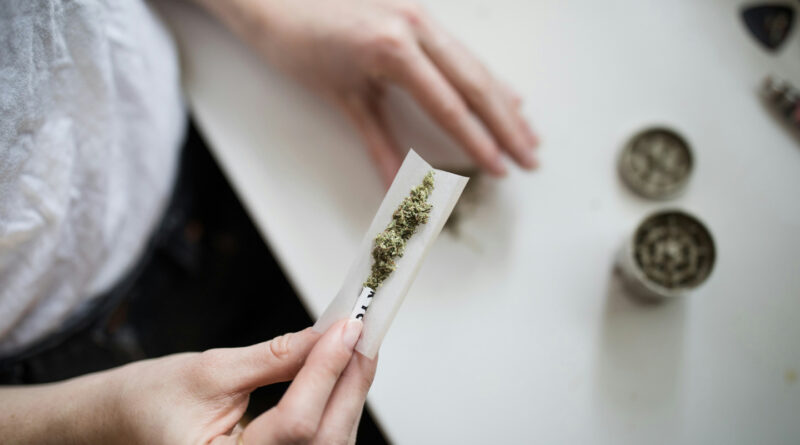 A person holding marijuana on a white paper.