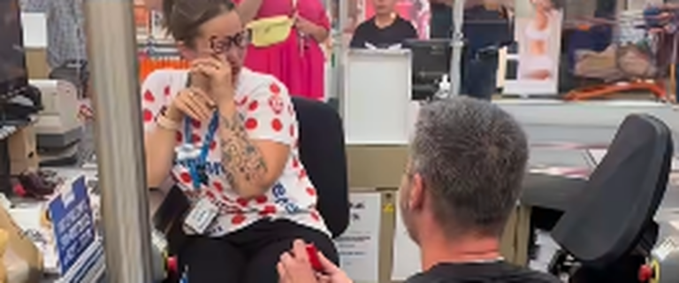 Une femme acceptant une demande en mariage à la caisse d’E. Leclerc devant des clients.