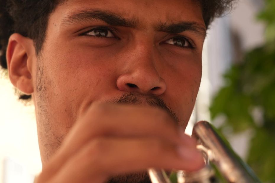 Un jeune trompettiste joue dans les rues, au-delà de la fête de la musique.