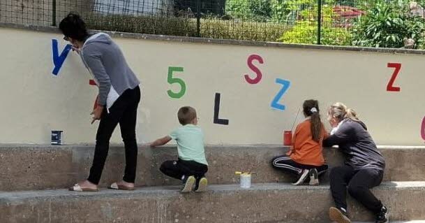 Une fresque colorée embellit la cour de l’école à Hirschland, favorisant l’engagement communautaire.