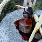 Un chef étoilé cuisine du cerf au feu de bois devant la grotte du Grand Roc