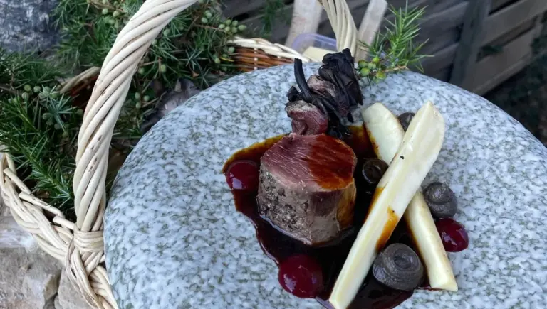 Un chef étoilé cuisine du cerf au feu de bois devant la grotte du Grand Roc