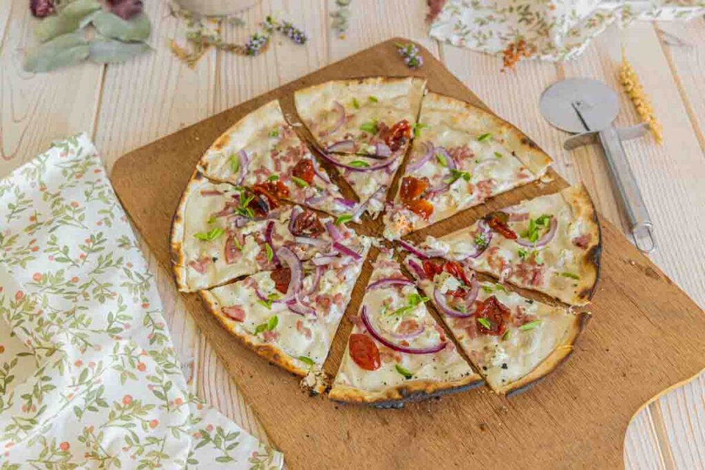 Tarte flambée estivale : recette de tomates séchées et feta, légère et gourmande.
