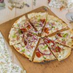Tarte flambée estivale : recette de tomates séchées et feta, légère et gourmande.